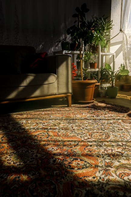 A child in beige shoes and jeans is using a vacuum cleaner with a grey and yellow body to clean a patterned rug in a living room. The rug has a floral design in muted tones of green, beige, and orange. The vacuum cleaner's hose is visible, connecting to the handheld nozzle. The room is well-lit with natural or artificial light, and the setting appears tidy and well-maintained. Haringey Carpet Cleaning offers professional surface cleaning and deep cleaning services to ensure optimal hygiene and cleanliness for domestic spaces.